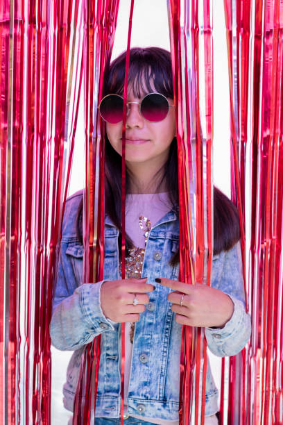 portrait of teenage girl with glasses behind a metallic pink party curtain - pre teen boy flash imagens e fotografias de stock