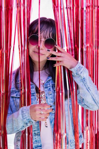 vertical portrait of a teenage girl at a party wearing glasses, behind a party curtain - pre teen boy flash imagens e fotografias de stock