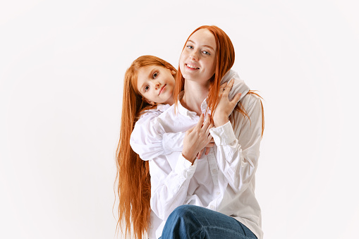Portrait of redhaired mother and daughter in casual wear look at camera with smile, have good family relationship. Happy, bright and young. Concept of love, care, family, fashion and ad
