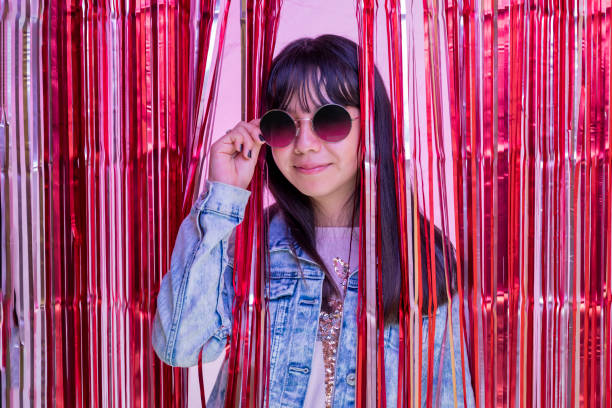 portrait of teenage girl with glasses behind a metallic pink party curtain - pre teen boy flash imagens e fotografias de stock