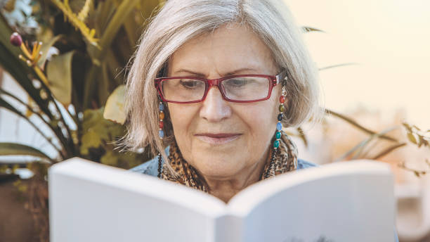 istock Older woman reads book 1423375745
