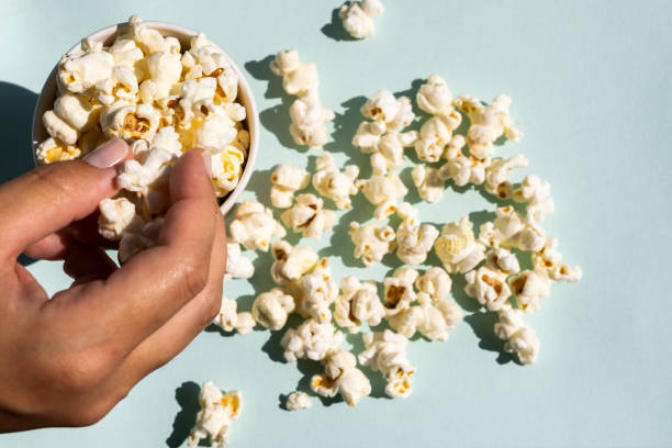 istock Hand taking salt popcorn from craft paper cup. 1423375768