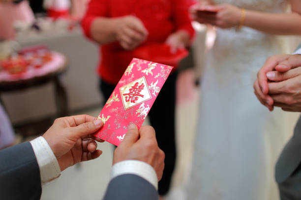 Cropped image of newlywed serving tea to elder on Chinese traditional tea ceremony and receiving red envelope