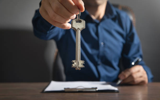 istock Man holding keys and signing contract. 1423379200