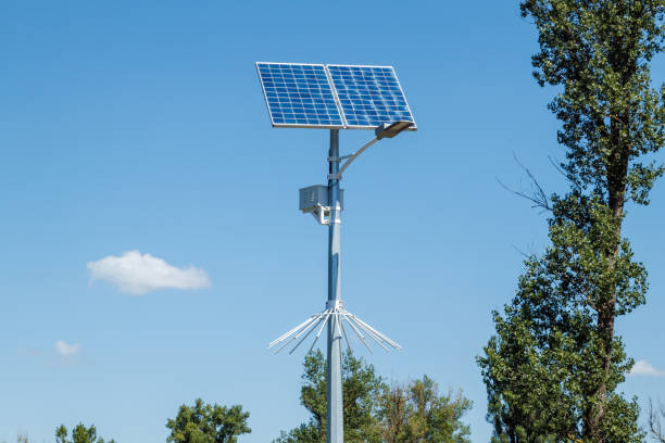 Solar device with street lamp on background of blue sky. Street light powered by solar panel with battery included. Alternative energy from the sun Solar device with street lamp on background of blue sky. Street light powered by solar panel with battery included. Alternative energy from the sun. solar street lights stock pictures, royalty-free photos & images