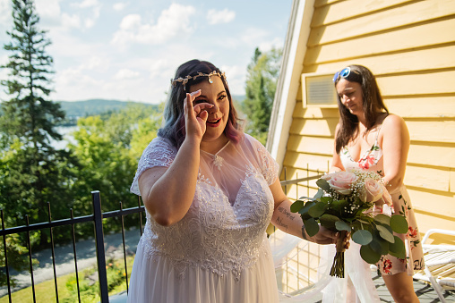 Body positive future bride getting emotional before LGBTQ+ wedding. This is part of a series about a lesbian couple getting married. Horizontal outdoors waist up shot with copy space.