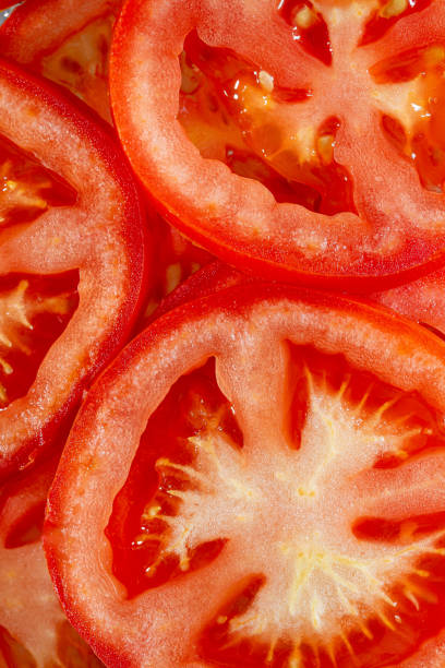макро красные помидоры, натуральные фоновые ломтики помидоров с ломтиками помидоров - carotene healthy eating macro close up стоковые фото и изображения