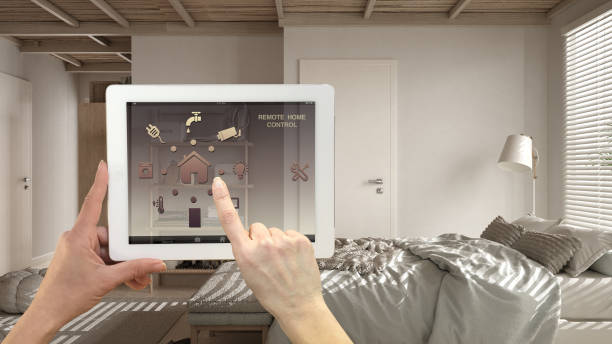 istock Smart remote home control system on a digital tablet. Device with app icons. Cosy peaceful wooden bedroom in the background, double bed with duvet, wooden architecture interior design 1423382664
