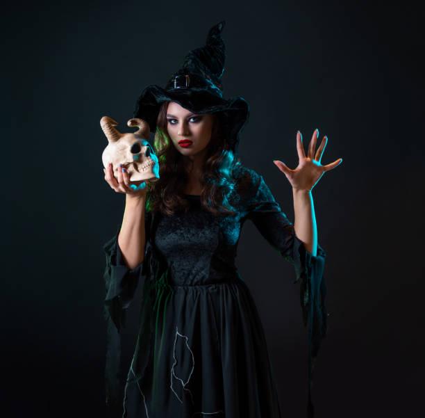 istock A young beautiful witch in a conical hat holds a devil's skull in her hands 1423383147