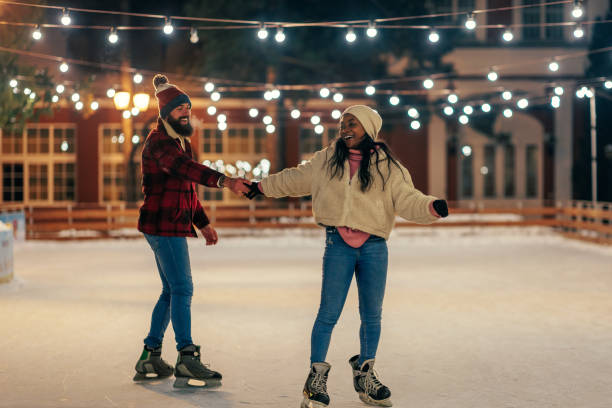 Couple on winter holiday ice skating. A young couple is on a winter holiday ice skating in the skating ring alone. ice skating stock pictures, royalty-free photos & images