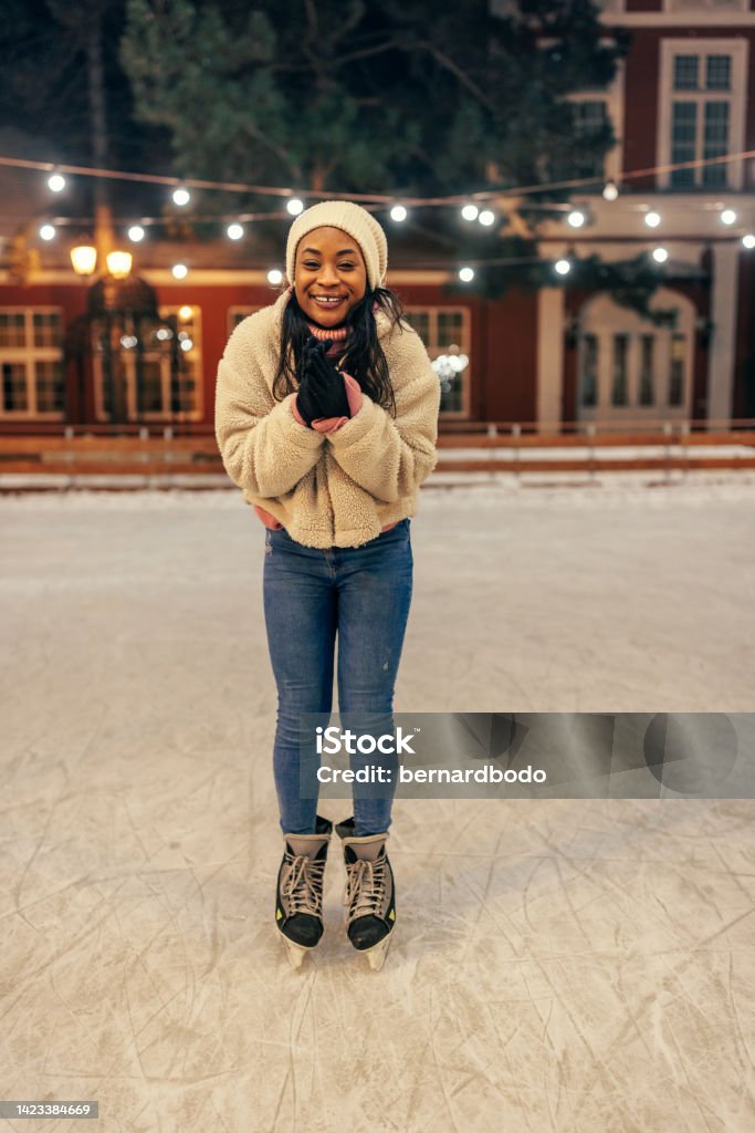 Young african woman on ice rink Young african woman standing on ice rink while is freezing outside Skating Stock Photo