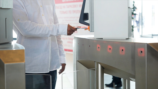 Modern electronic entrance in the business building, technology background. A man in white shirt scanning his ticket and passing through.