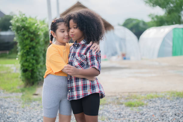 Two kids friends hugging outdoor having fun in summer.