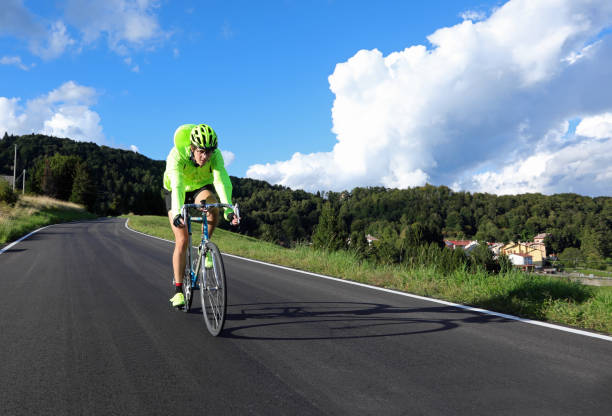 ciclista con bicicleta de carreras y chaqueta impermeable fosforescente en la carretera - road reflector fotografías e imágenes de stock