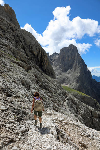 istock woman hiker with backpack on shoulders walks on stone path in high Dolomites mountain of european alps 1423387247
