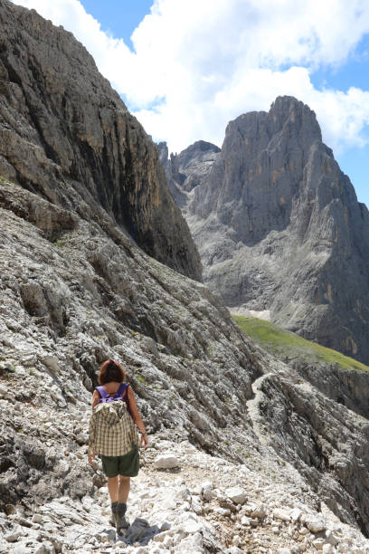 istock woman hiker with backpack on shoulders walks on stone path in high Dolomites mountain of european alps 1423387289