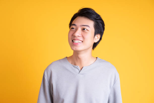 istock Asian young man posing on a yellow background 1423387301