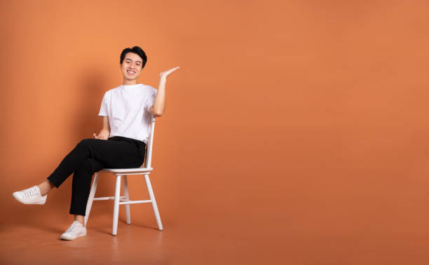 istock man sitting on chair  isolated on orange background 1423387334
