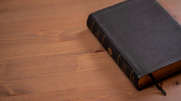 istock Dark closed book (Bible) on wood table 1423388867