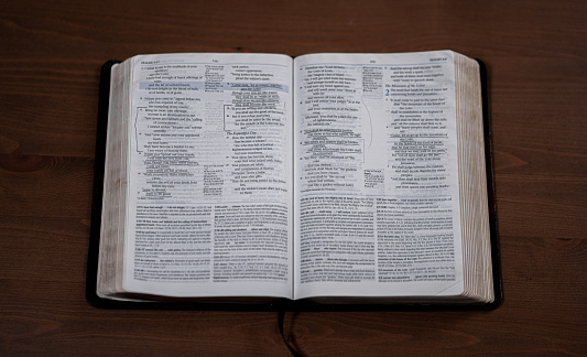 Open dark book (Bible) laying on a wooden background with room for text