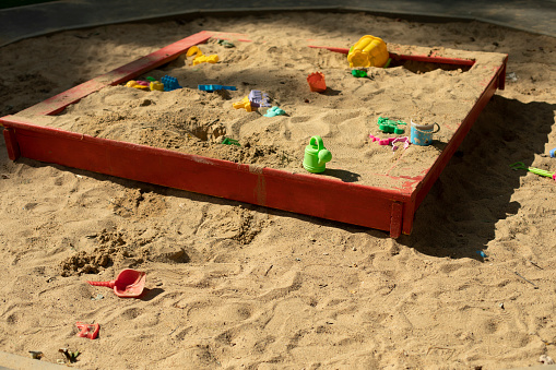 Children's playground with sand. Children's sandbox on street. Place for game kids. Sand with toys. Forgotten toys.