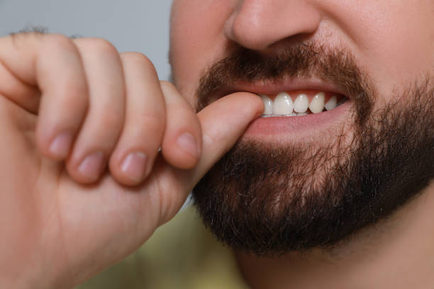 istock Man biting his nails on grey background, closeup. Bad habit 1423391574