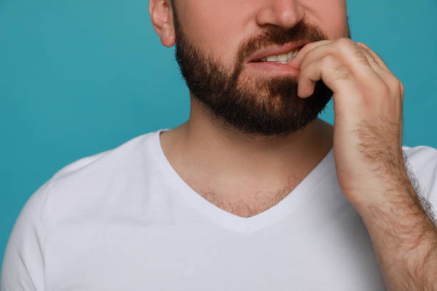 istock Man biting his nails on light blue background, closeup. Bad habit 1423391864