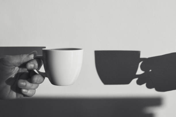 Cup of coffee on saucer with a closed devotional book and an open bible sitting on a round white side table in front of a sofa with copy space