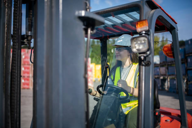 istock Young woman working in warehouse driving forklift. 1423392116