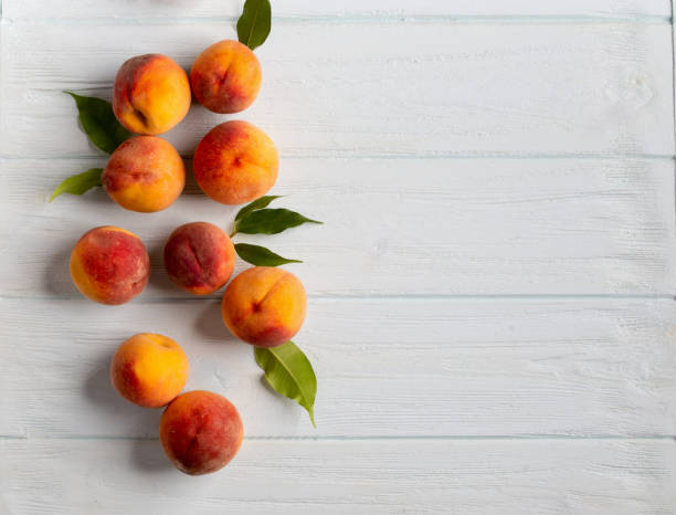 istock Ripe peaches on white wooden background top view 1423392703
