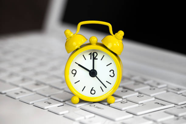istock Yellow alarm clock on a laptop, daylight savings time 1423393617