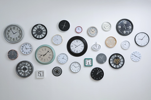 Collection of different clocks hanging on white wall