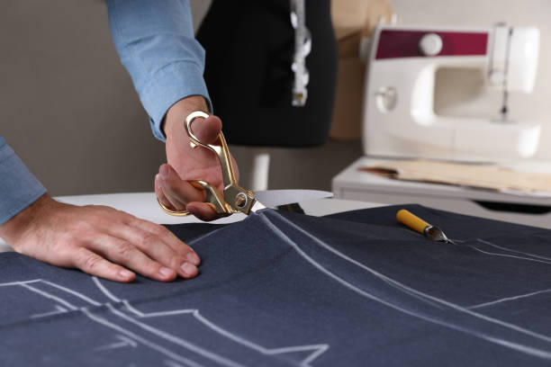 istock Tailor cutting fabric with scissors at table in atelier, closeup 1423395299