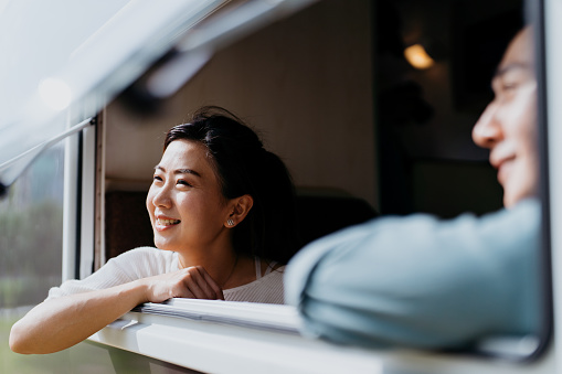 Image of an Asian Chinese couple relaxing in motor home and looking out from window