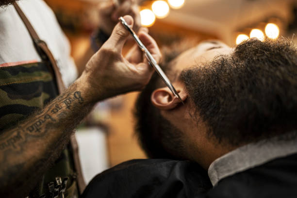 istock Barber styling beard of a customer in barber shop using scissors 1423398921