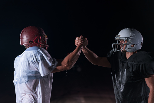 two american football players opposite face to face in dark night with rain. Competition and race concept. High quality photo