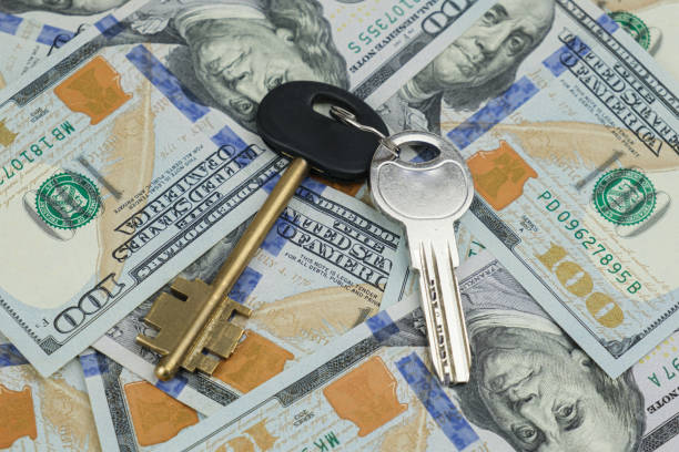 istock Two keys lie on scattered US dollar bills 1423403344