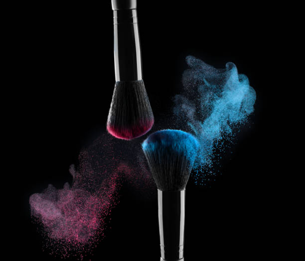 Black cosmetics eyeshadow brushes with colorful make-up powder splashes on black background stock photo