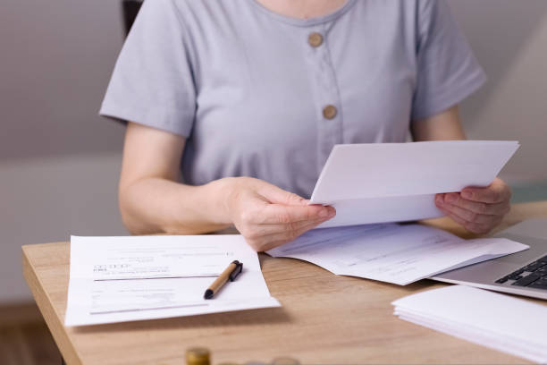 istock A woman sits at a table and looks through papers, receipts, utility bills. 1423405859