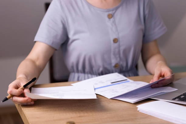 istock A woman sits at a table and looks through papers, receipts, utility bills. 1423406517