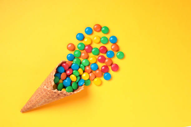 istock Waffle Cone with Color Candies on yellow background 1423410180