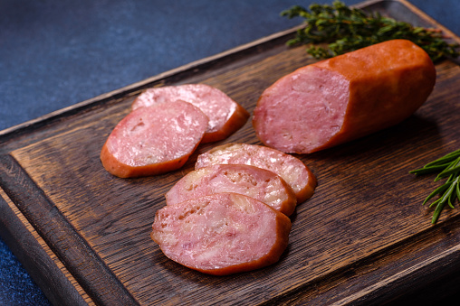 Bratwurst Raw meat sausages on wooden board with spices. Dark background. Top view.