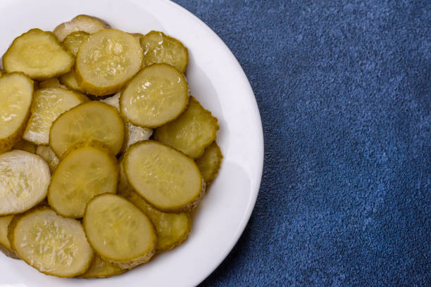 istock Delicious salted, canned cucumbers cut into slices on a white ceramic plate 1423410409