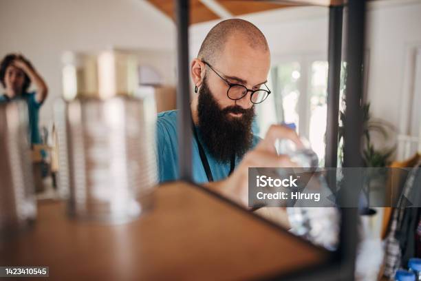 Man Intensely Sorting Man Sorting Donations On A Shelf Stock Photo - Download Image Now - A ...