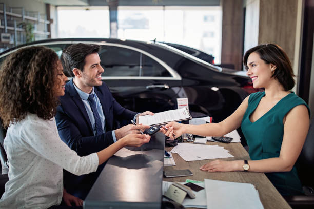 Couple is buying/lease new car and signing a contract stock photo
