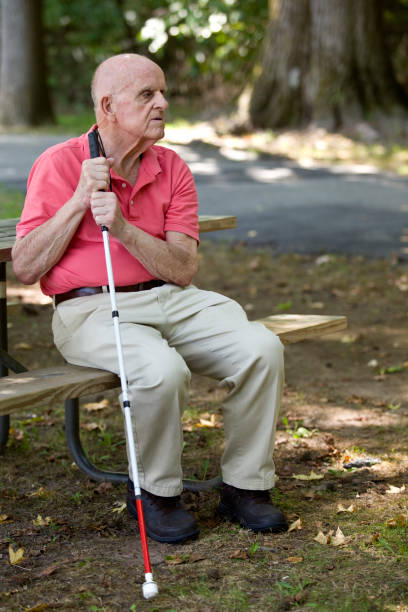 istock Blind person sitting in park holding blind persons cane 1423410843