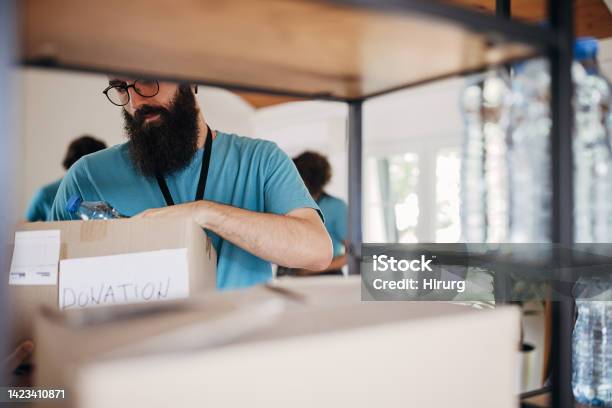 Man Intensely Sorting Man Sorting Donations On A Shelf Stock Photo - Download Image Now - A ...