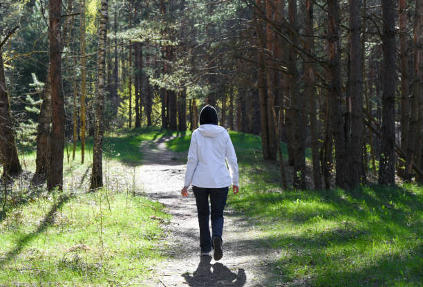 istock Woman walking along a path in the forest 1423413489