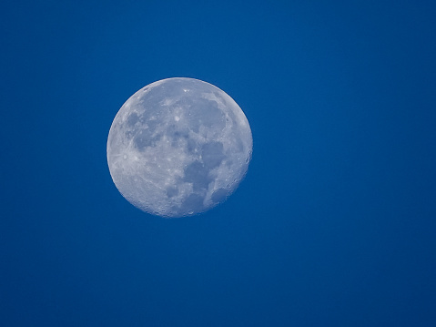 Full moon in a bright blue sky.