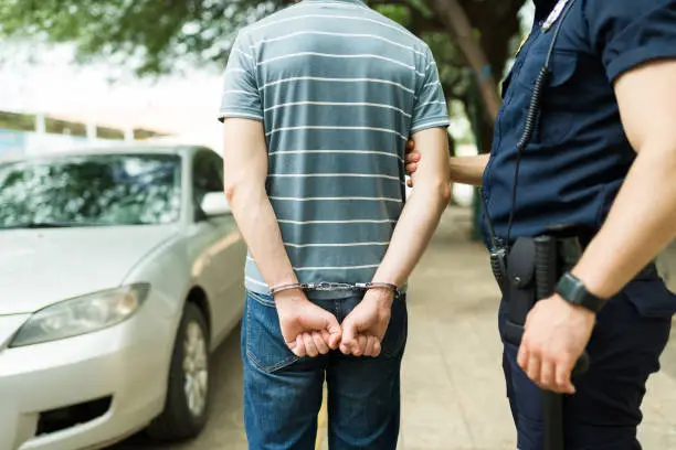 Photo of Rear view of a young man getting arrested because of a car crash